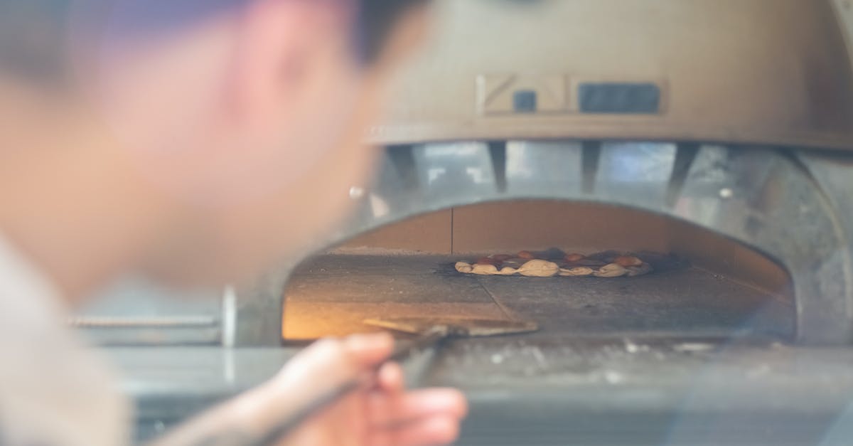 Cooking pizza in tiny gas oven with pizza stone - Man Looking into Oven