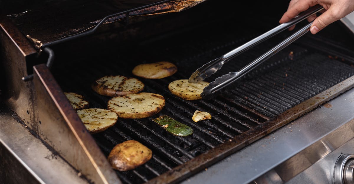 Cooking temperature chart - Unrecognizable man with tongs turning over tasty cut potatoes on metal grate while cooking on modern hot barbecue grill machine