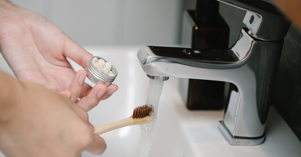 Copper-lined stainless steel vs pure copper skillet - Crop anonymous person with toothpaste tablets and ecological toothbrush under aqua flowing from washbasin tap in bathroom