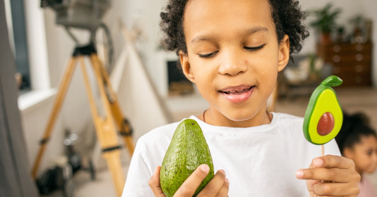 Correlation between perceived sweetness and sugar content - Cute black boy with lollipop and avocado in hands