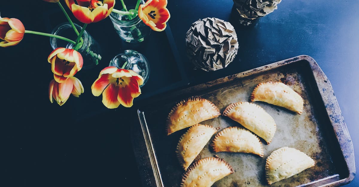 Costa Rican empanada-like food? - Yellow and Red Flower on Clear Glass Flower Vase Beside Brown Steel Tray With Pastry