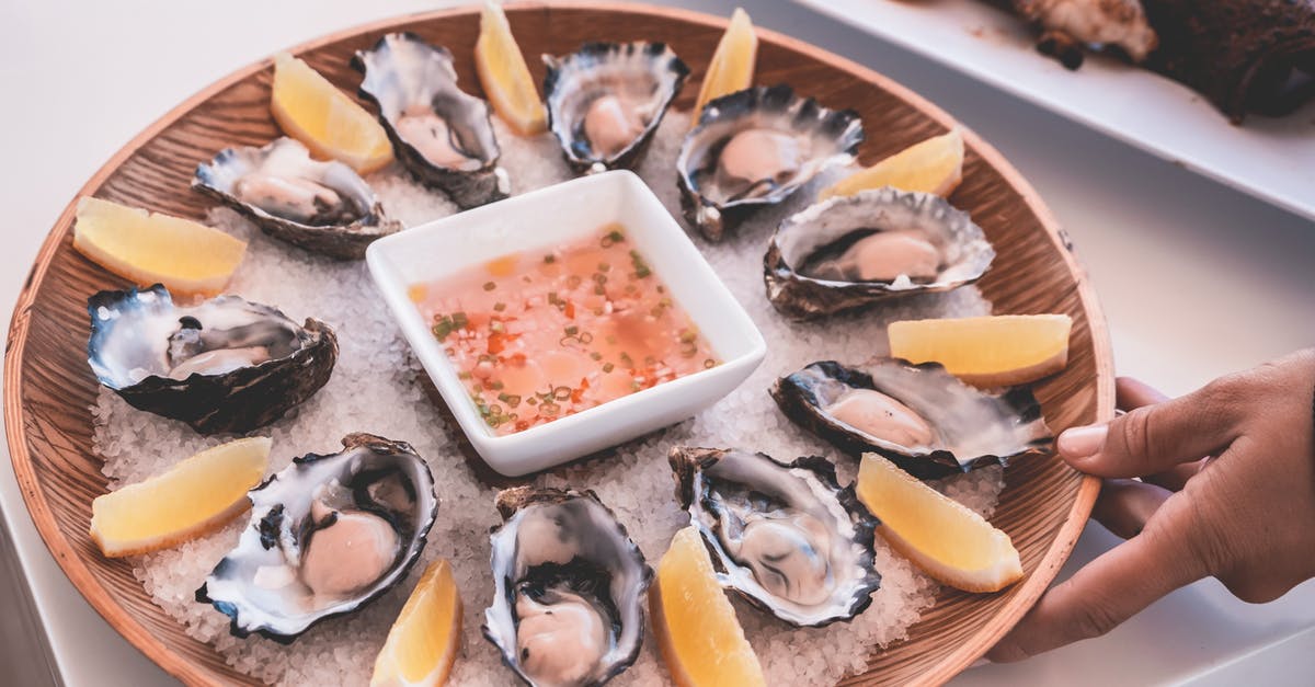 Could I possibly tell imitation lobster from real lobster? - Anonymous person serving plate of fresh oysters with sauce and lemons on table