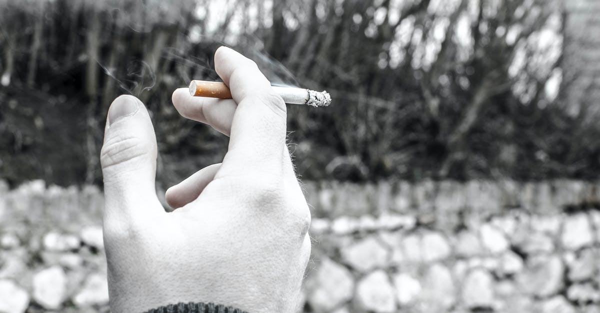 Could it be bad black olive that I've eaten? - Selective Color Photography of Person Holding Cigarette Stick