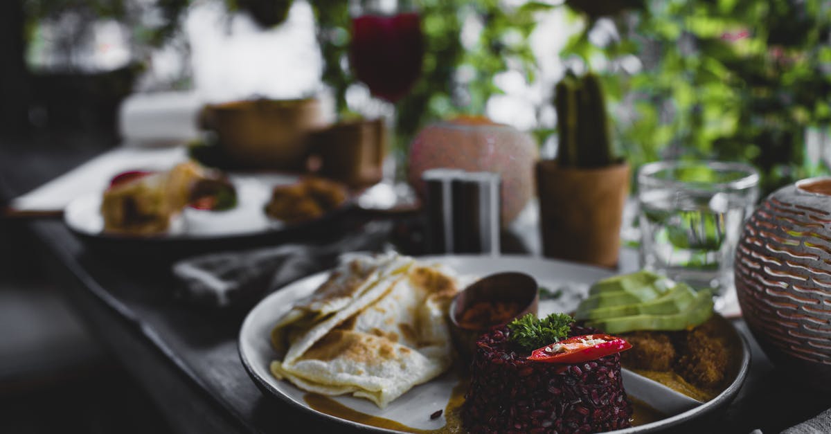 Cracked Mexican/Spanish style rice - Plate with delicious red rice served with roti bread and avocado against stylish interior of tropical cafe