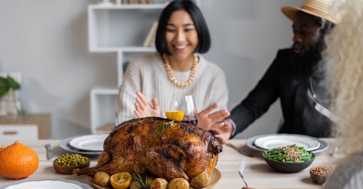 Creating a thanksgiving brine for a 7-8 lb Turkey? - Cheerful multiethnic people having dinner together at table with roasted turkey while celebrating Thanksgiving Day