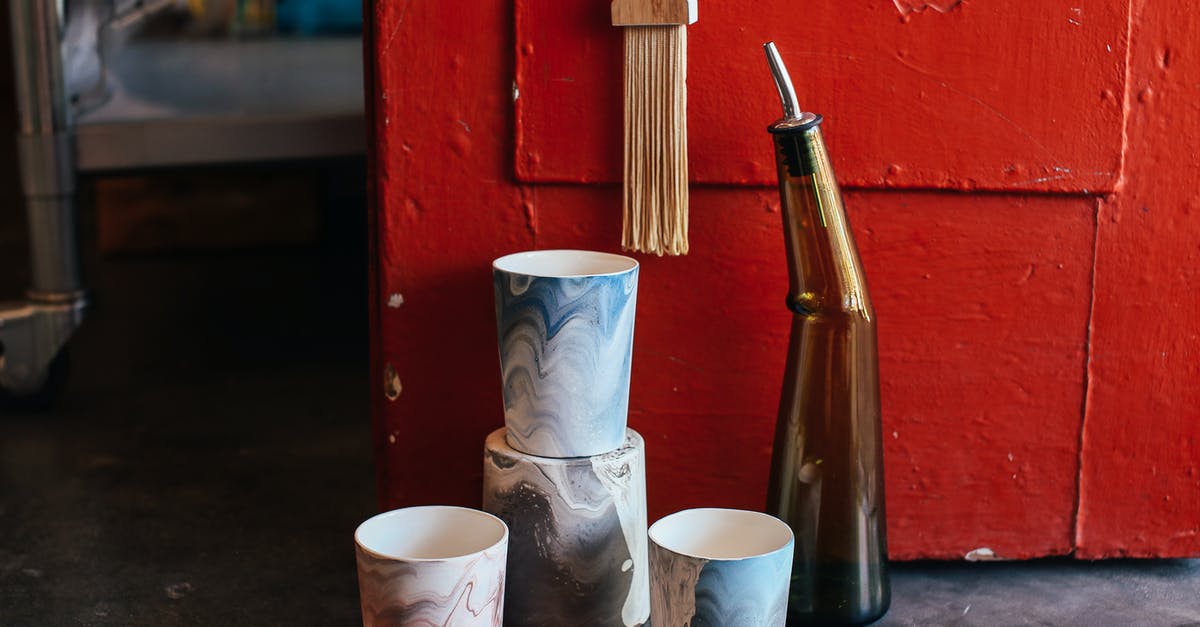 Crock pot times vs internal temperature vs meat size - Collection of ceramic pots with creative ornaments near glass bottle placed on floor near shabby red door in modern workshop