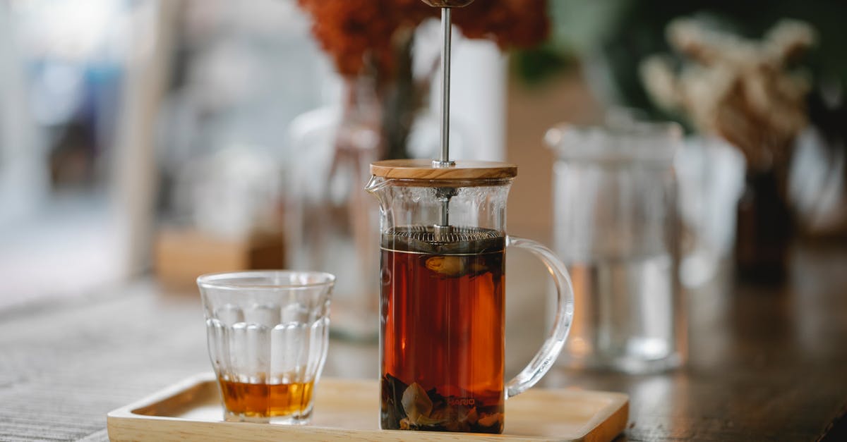 Crock pot turned to warm for 45mins- 1hr - Transparent French press with hot aromatic herbal tea brewing on wooden tray near glass on table in cafe