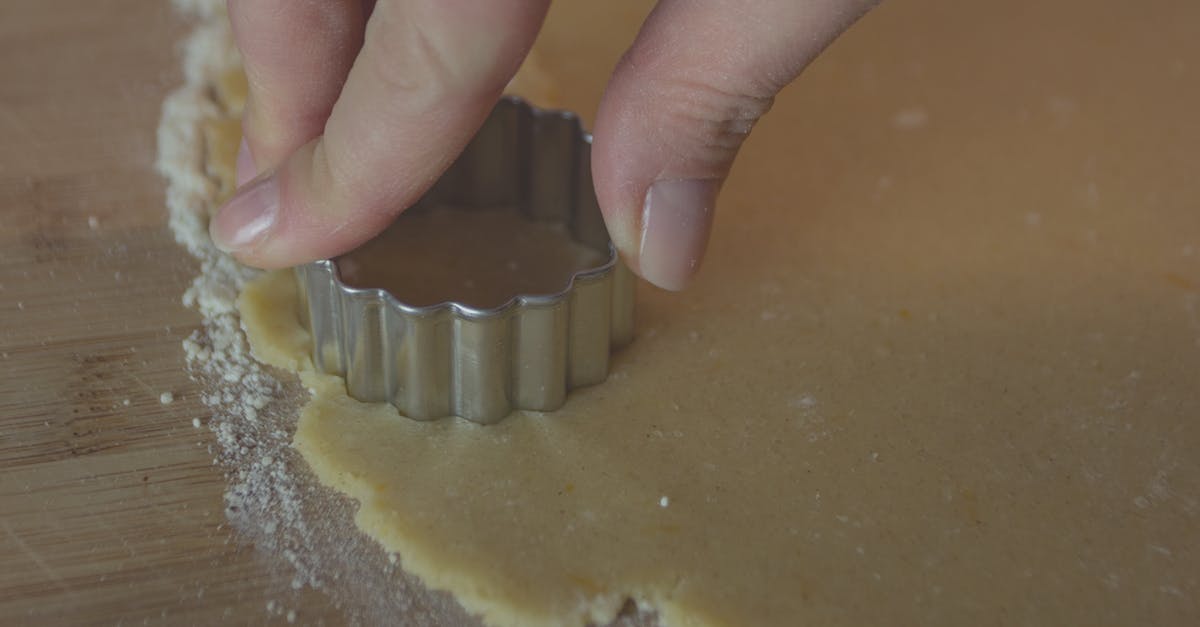 Crumbly cookie dough [closed] - Crop person cutting dough on table