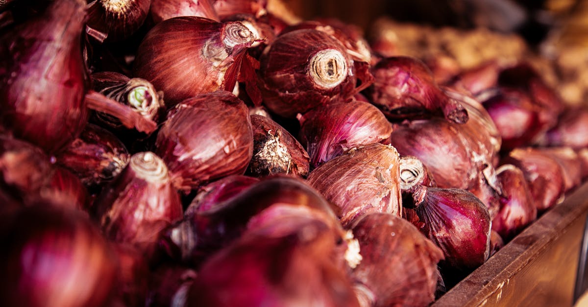 Crunchy onions in soup? - From above of wooden box with pile of bright raw onions with dry red husk in local bazaar