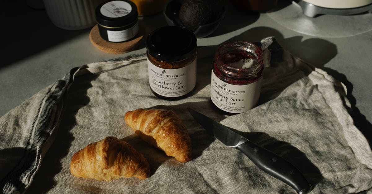 Crusty french bread - Still life of delicious brown croissants with opened jam and sauce pots on gray kitchen counter placed on with fabric napkin near knife in rustic style