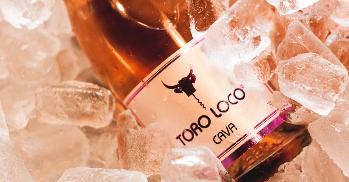 Crystals on bottle of sweet alcohol - From above of bottle of wine with logo of bull placed in cold ice cubes