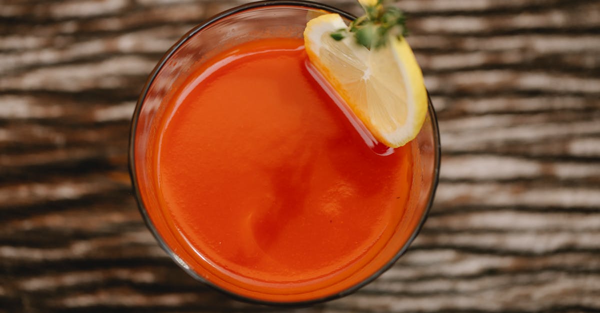 Cumin-flavored vodka - From above of colorful tasty alcoholic drink with tomato juice and thyme sprig on top of glass