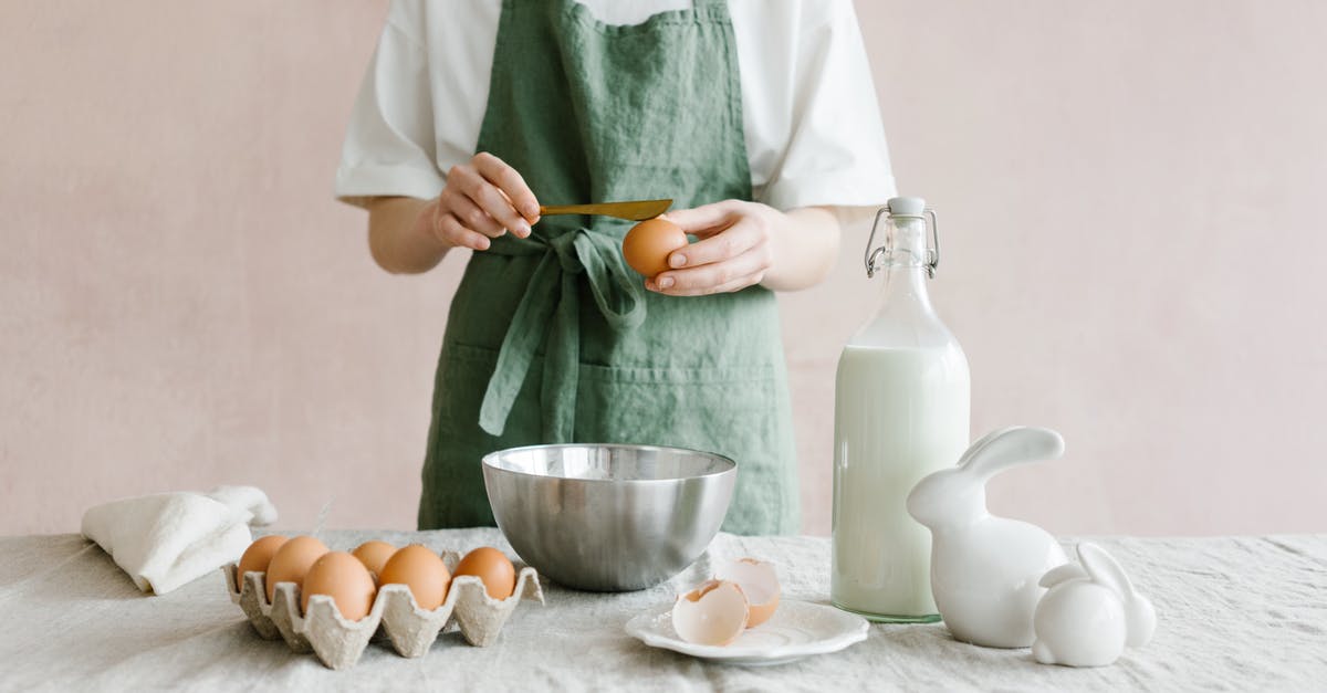 Custard - How much milk can one egg set? - Crop anonymous female with egg in hand at table with iron bowl and glass bottle of milk