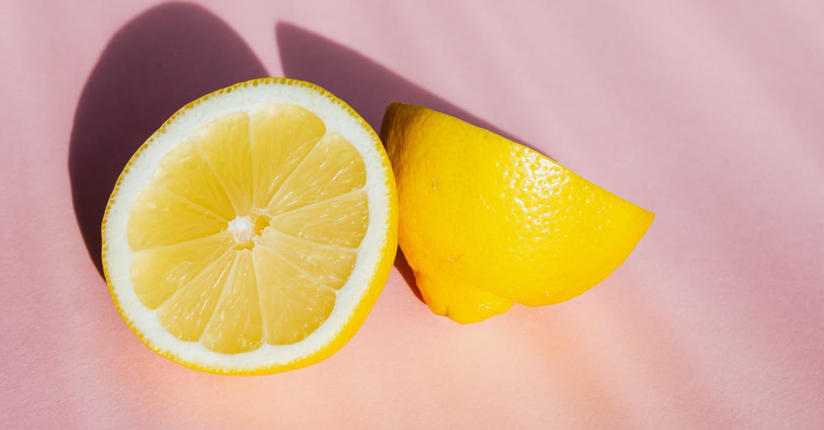 Custard surface has tiny pockmarks when I use fruit pulp - Top view of halves of fresh juicy lemon composed on pink background in sunbeams