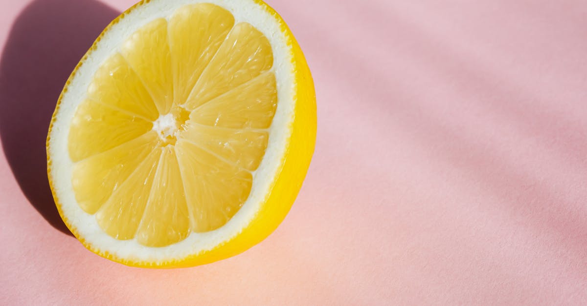 Custard surface has tiny pockmarks when I use fruit pulp - From above half of fresh sliced lemon placed in pink background in bright sunlight