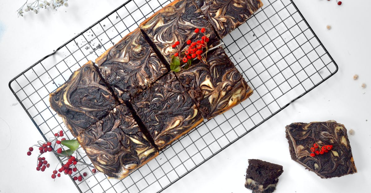 Cut food with fork and sharp knife - metal in food? - Top view of appetizing chocolate brownie cut into squares and decorated with ripe berries placed on metal grid on table