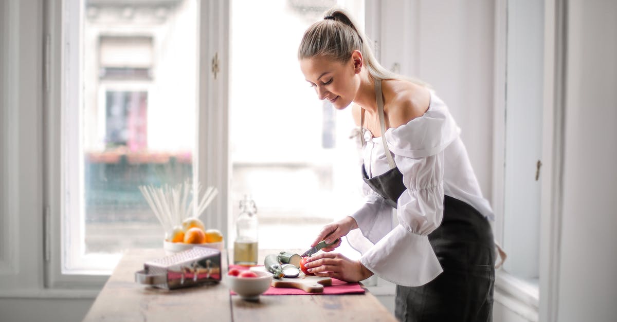 Cutting windows into a premade gingerbread - Woman in White and Black Dress 