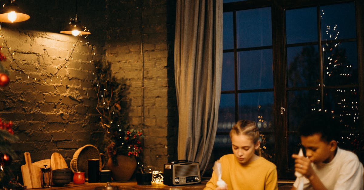 Cutting windows into a premade gingerbread - Two Kids Holding Cream Bags