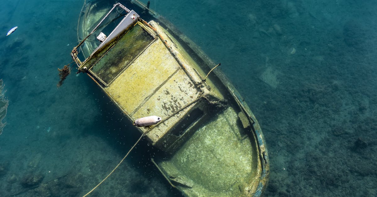 Damage to pan bottom - Small wrecked shabby boat undersea in daytime