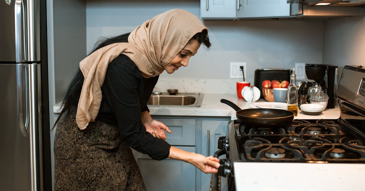 Dangers of leaving food in an off gas oven - Cheerful ethnic woman switching stove before cooking