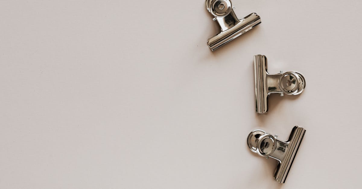 Dark grey residue from newly purchased stainless steel kitchen items? - From above of identical metallic clips made of solid material with smooth surface on beige background