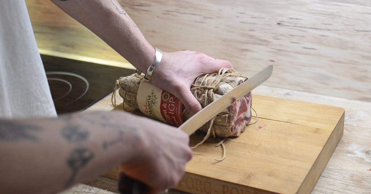 Dealing with a hank of natural sausage casings - Crop man cutting meat on wooden board at home