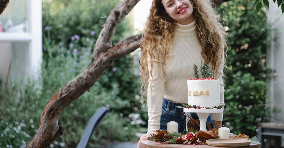 Decoration food long-term preservation - Young female with long hair in casual clothes with fresh appetizing cake on small round table in backyard