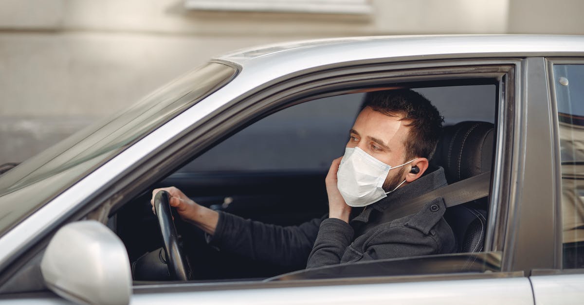 deli ham left in warm car - Serious bearded male driver wearing warm jacket and protective facial mask using wireless earphones sitting in auto with opened window during coronavirus pandemic