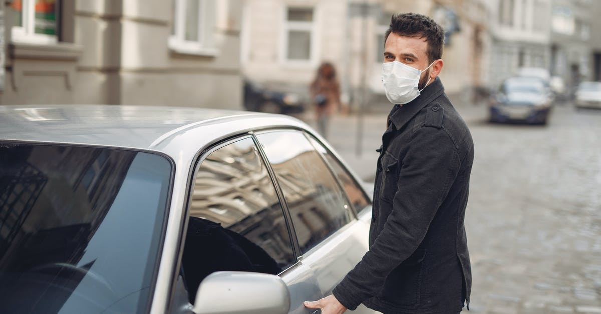 deli ham left in warm car - Bearded male driver wearing warm jacket and protective facial mask opening door of auto on blurred city background during Coronavirus pandemic and looking at camera