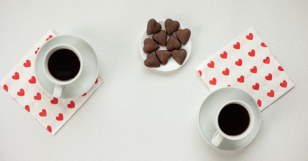 Difference between instant cocoa and drinking chocolate - Top view of cups with hot coffee and chocolate candies in heart shape on white background