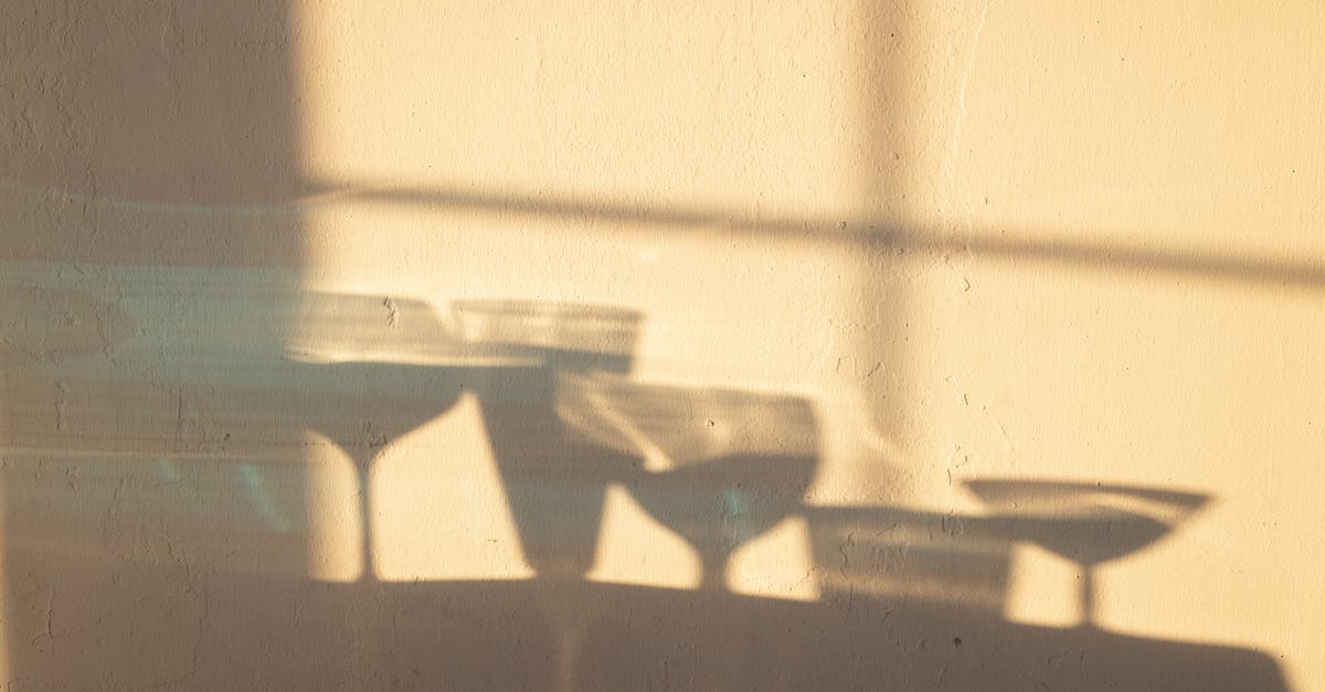 Difference between Spumante & Champagne - Shadows of different crystal glasses filled with drinks reflecting on white wall in sunlight