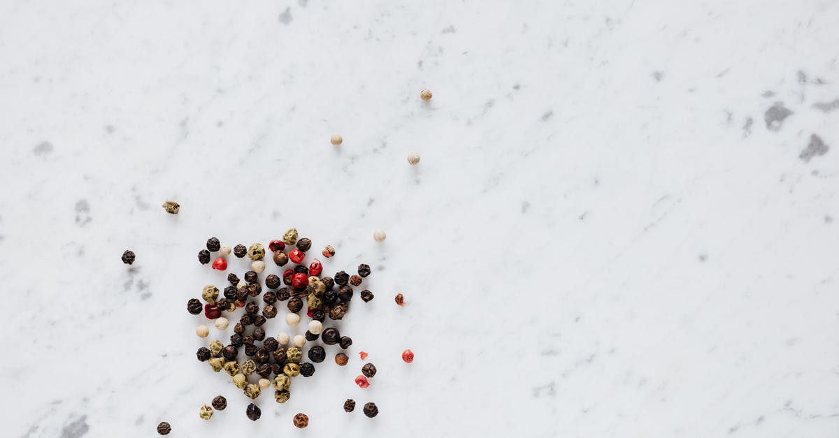 Differences in creme fraiche recipe - Top view of heap of assorted whole peppers on smooth marble light surface