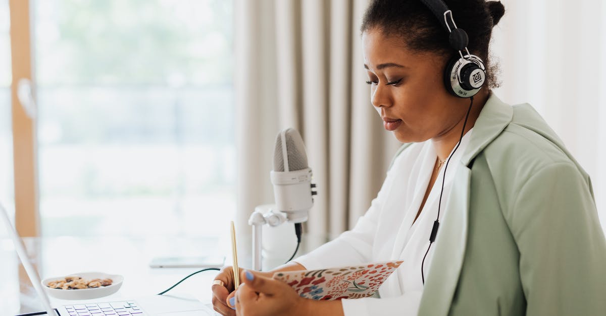 Difficulty Working with Koji - Woman Sitting in Headphones with a Laptop and a Microphone Next to Her Reading from a Notebook 