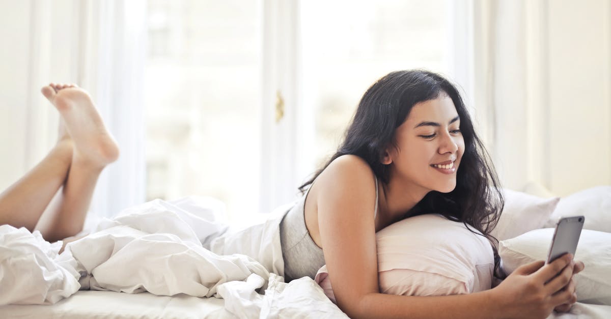 Dishwasher with side brackets for on top shelf: what are they for? - Happy young woman browsing phone on bed Dishwasher with side brackets for on top shelf: what are they for? - Happy young woman browsing phone on bed