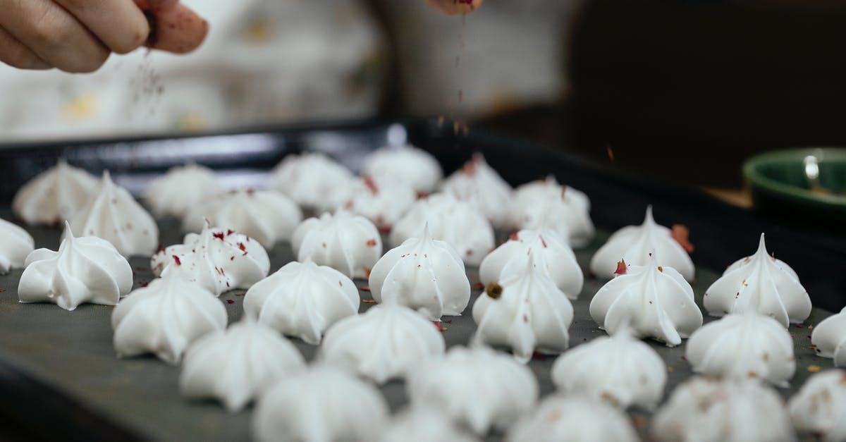 Dissolving xylitol in a raw, home-made chocolate - Crop faceless chef pouring chocolate powder on meringue cookies