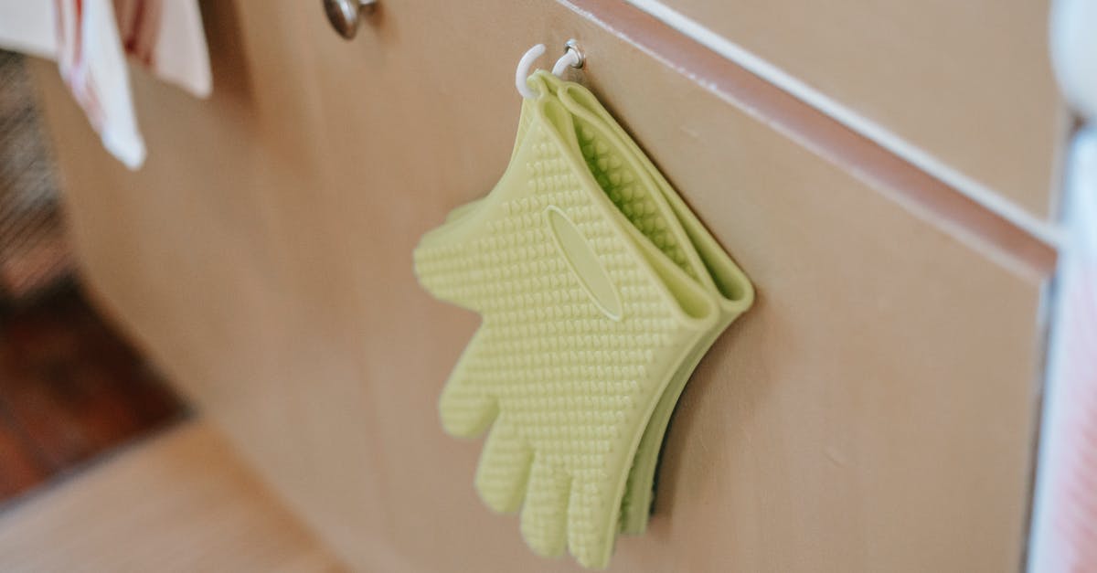 Distribution of heat using a silicone oven tray - Pair of oven gloves on cabinet door in kitchen