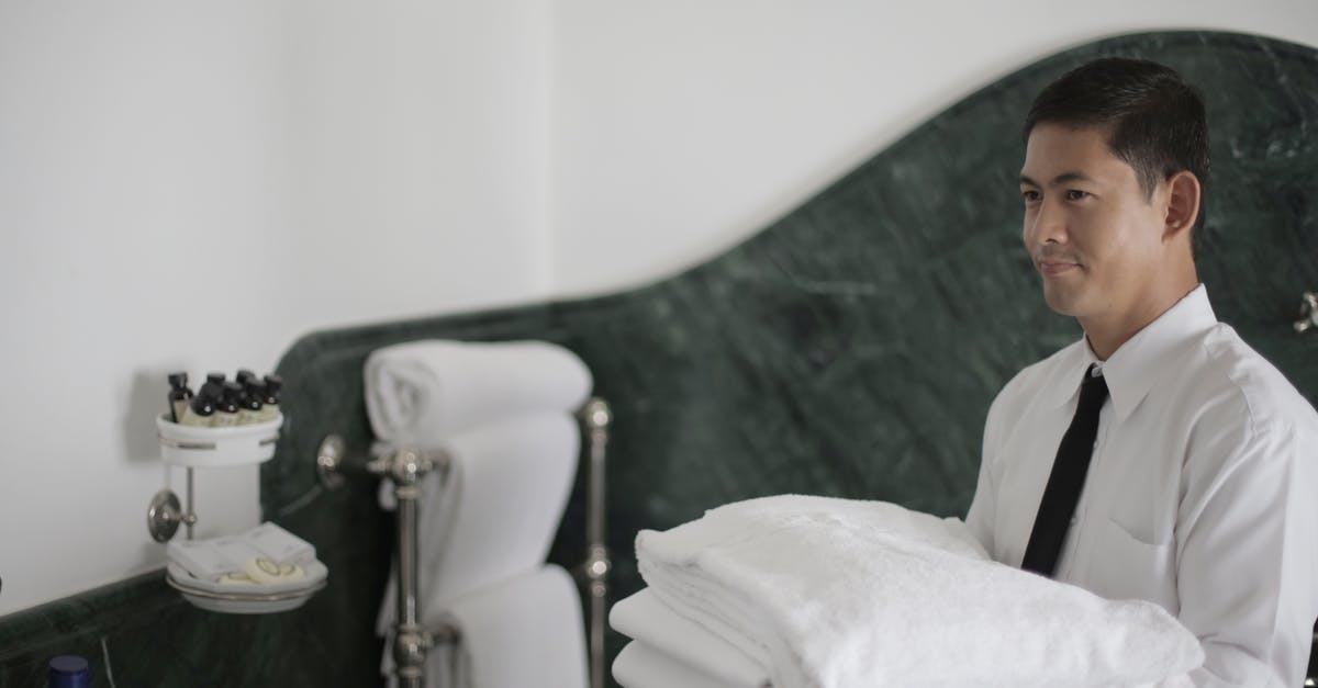 Do Asian groceries carry vital wheat gluten? - Side view of smiling ethnic male hotel employee holding stack of clean white towels while cleaning bathroom