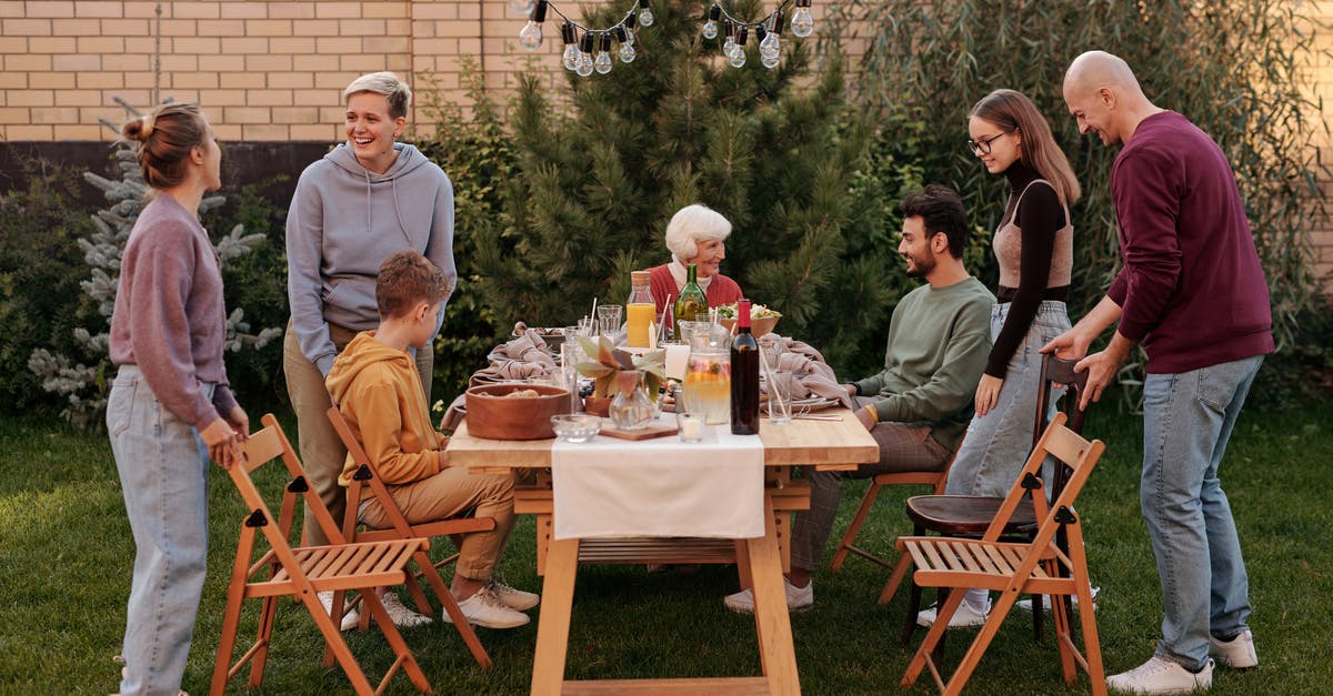 Do beignets have to sit overnight? - Happy family members talking and sitting down to eat tasty food at big wooden table in backyard in daytime