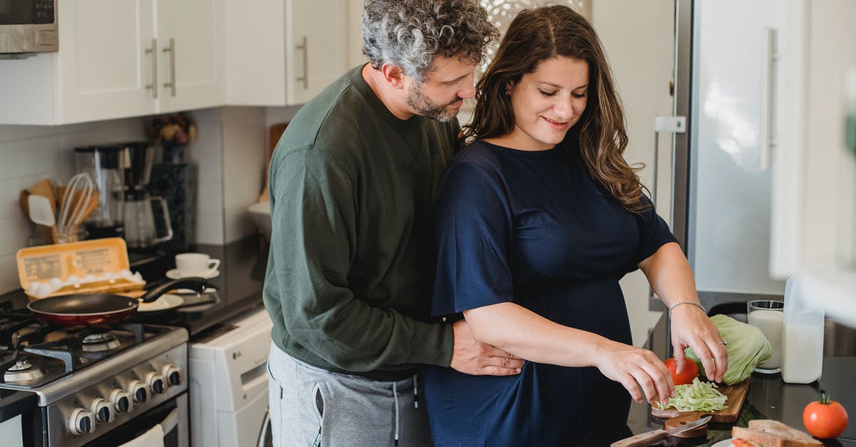 Do burgers cook better when close or far apart? - Calm husband embracing pregnant wife preparing tasty sandwiches while spending time together in kitchen in cozy apartment in daytime