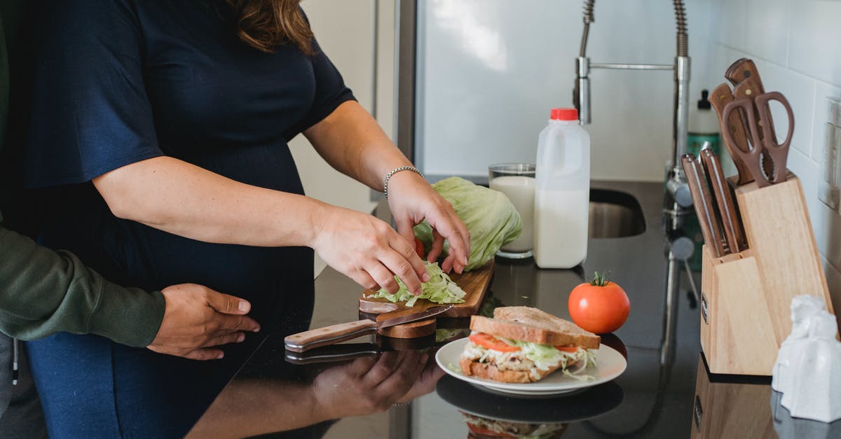 Do burgers cook better when close or far apart? - Crop anonymous couple hugging and cooking fresh healthy sandwiches while spending time together in kitchen at home