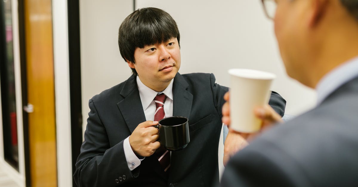 Do German or Japanese knives hold their edge longer? - Man in Black Suit Holding Black Ceramic Mug