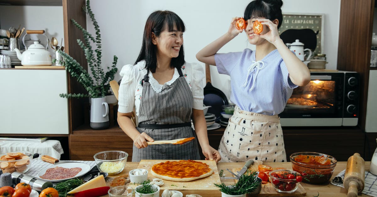 Do I have to cook salame - Positive women having fun cooking pizza