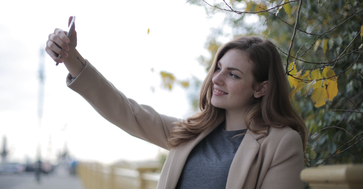 Do I have to use butter in a "butter yellow cake?" - Young woman in coat taking selfie with smartphone on street in overcast weather