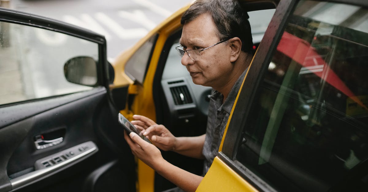 Do I have to use butter in a "butter yellow cake?" - Crop Asian man sitting in parked yellow taxi car with open door and using smartphone while looking away