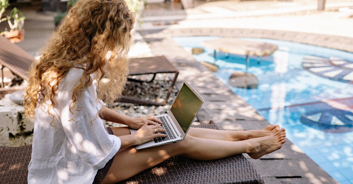 Do I need to adjust recipes when using hard water - From above side view of unrecognizable barefoot female traveler with curly hair typing on netbook while resting on sunbed near swimming pool on sunny day