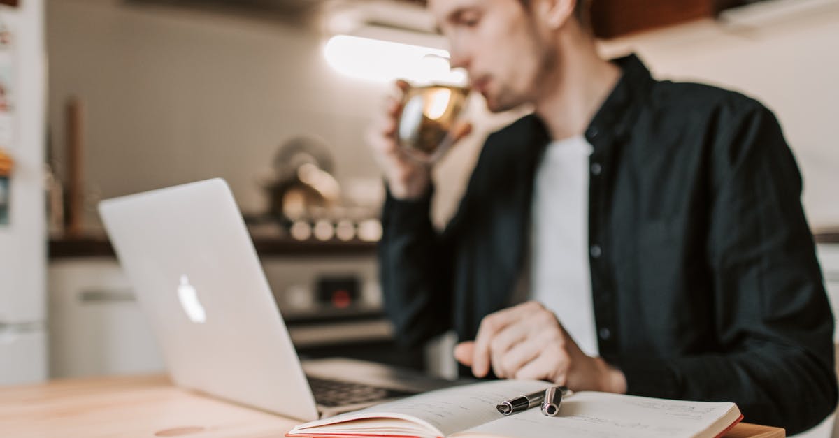 Do I need to adjust recipes when using hard water - Crop male freelancer drinking water while watching laptop in kitchen