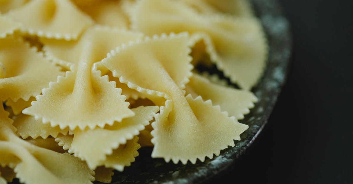 Do I need to let ravioli made with fresh dough dry? - High angle of raw dried traditional Italian farfalle pasta in bowl on black background