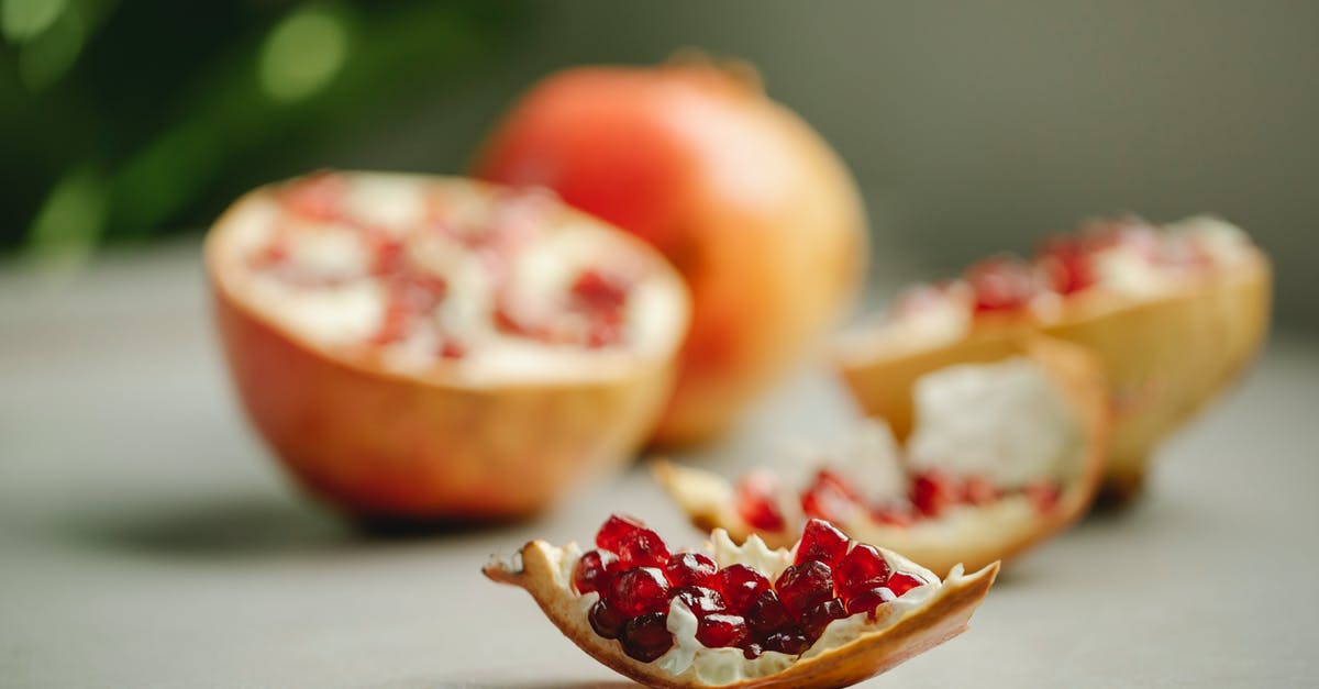 Do I need to peel a red kuri squash? - Chunk of ripe pomegranate with red seeds placed on surface near halves of tasty fruit on blurred background in kitchen