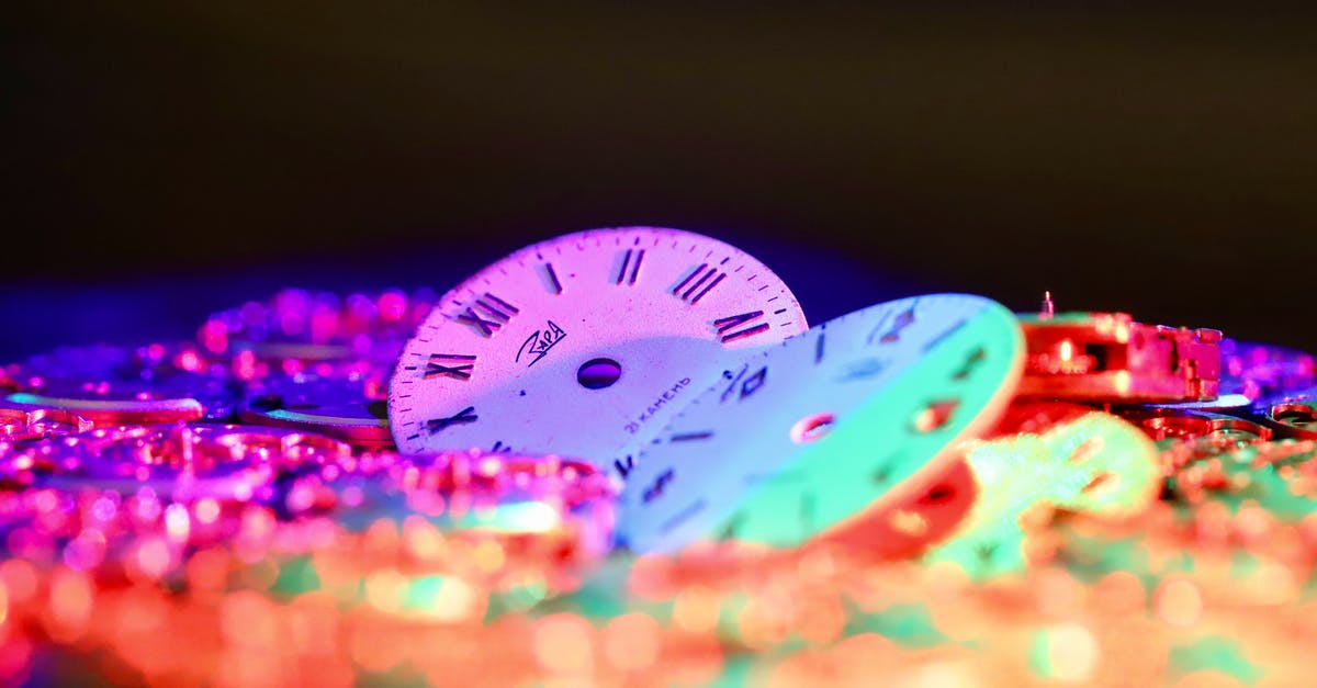 Do metal skewers make a considerable different cooking time than wooden? - Round clock faces with Roman and Arabic numerals placed among stack of watch movements in dark room on black background