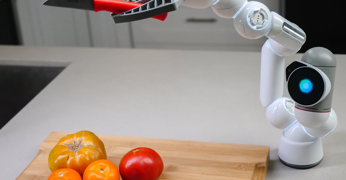 Do plastic cutting boards dull knives faster than wood boards? - White and Black Robot Toy Beside Orange Fruits on Brown Wooden Chopping Board